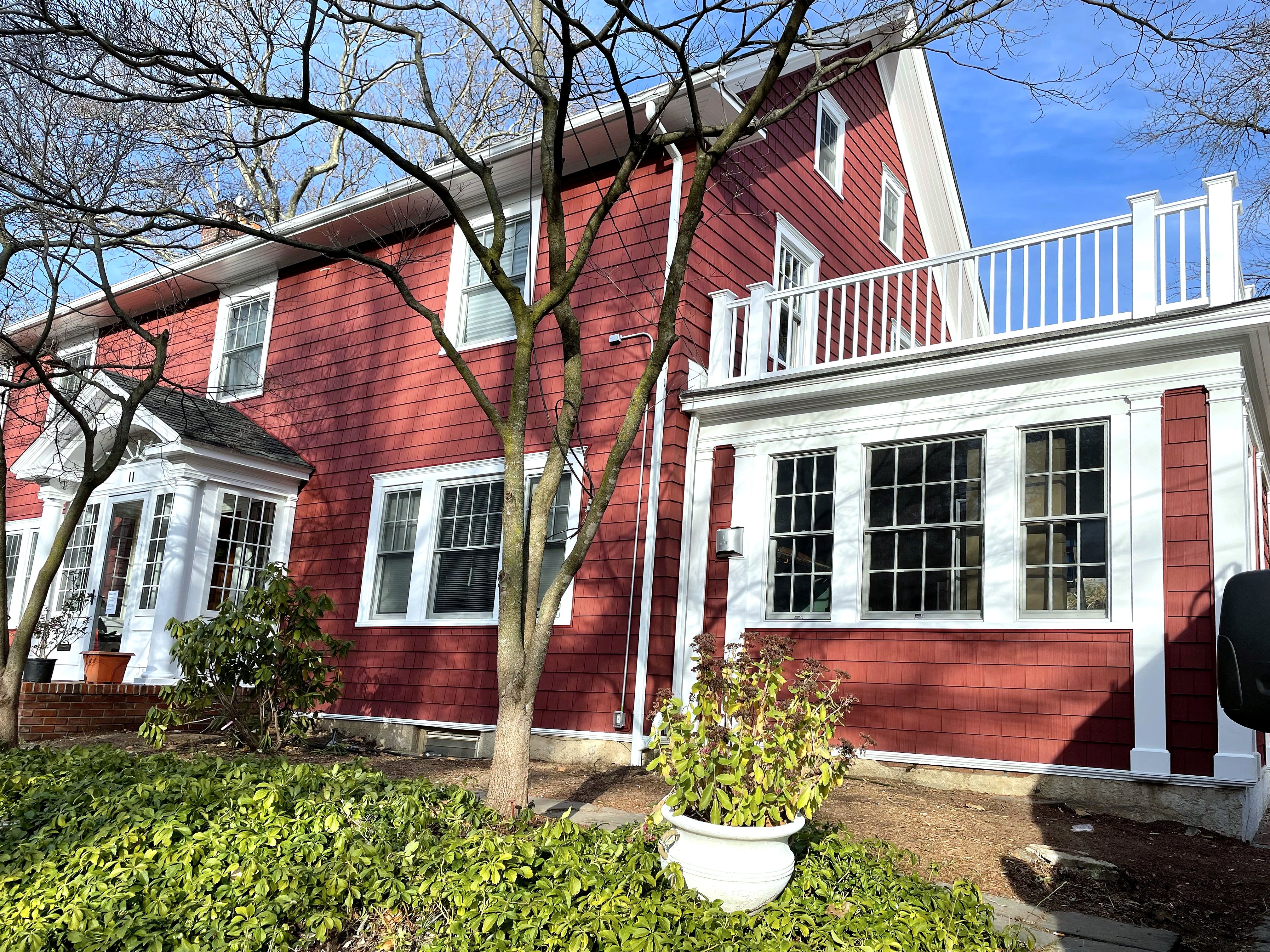 Red shingle-sided house with white trim, new windows and balcony